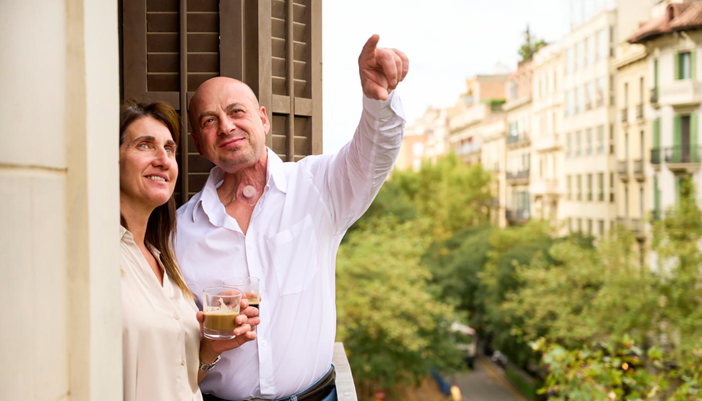 Couple on balcony in city man with stoma living with laryngectomy