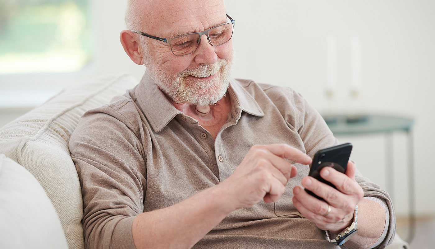 man using phone with stoma living with laryngectomy